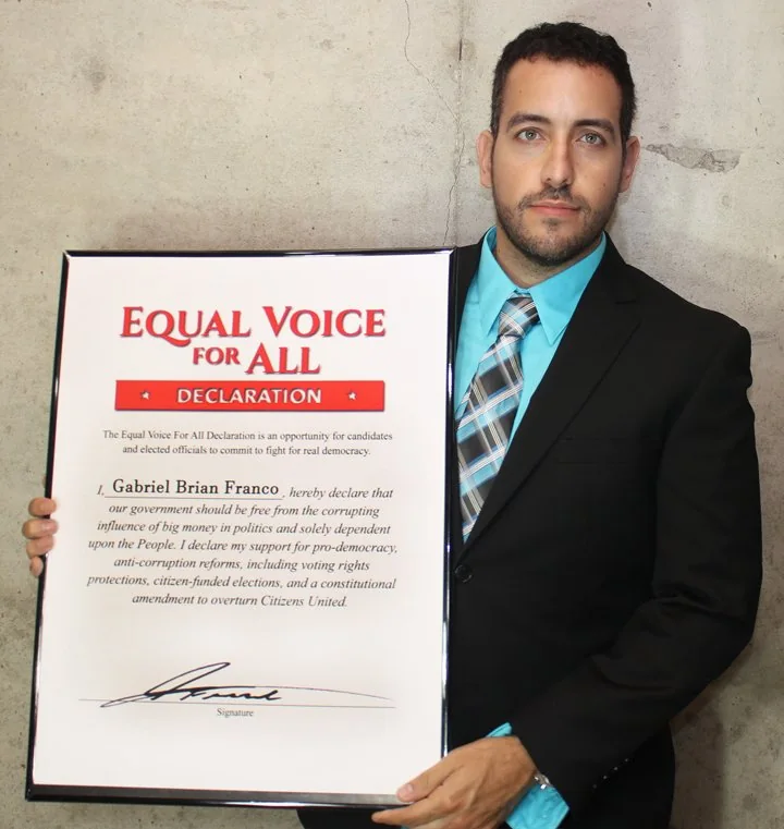 Gabriel Franco holding an Equal Voice for All declaration pledging support for democracy reform