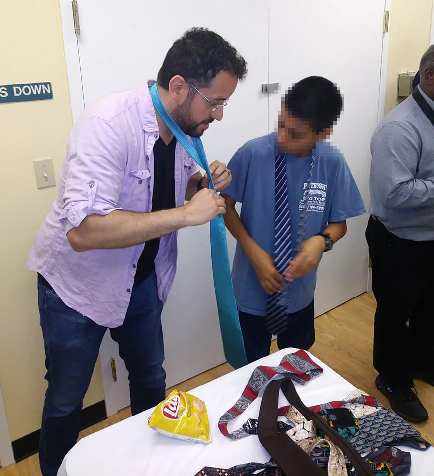 Gabriel Franco teaching a young participant how to tie a necktie
